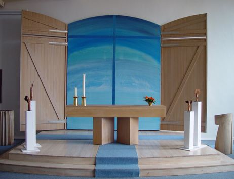 Moderner Kirchenaltar mit Holztisch, Kerzen und blauer Hintergrundgestaltung.
