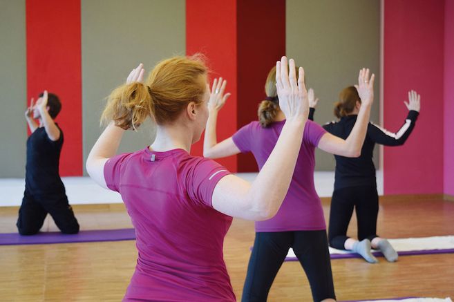 Menschen in einem Fitnesskurs machen Rückenübungen auf Matten.