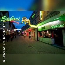 Straßenszene in St. Pauli mit leuchtenden Neonschildern und Menschen auf der Straße.