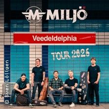 Band Miljö posiert vor einer blau-weißen Kachelwand mit Instrumenten. Schriftzug: Veedeldelphia Tour 2026.