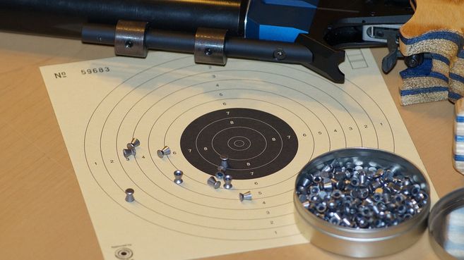 Zielscheibe mit Luftgewehr und Diabolos auf einem Tisch.