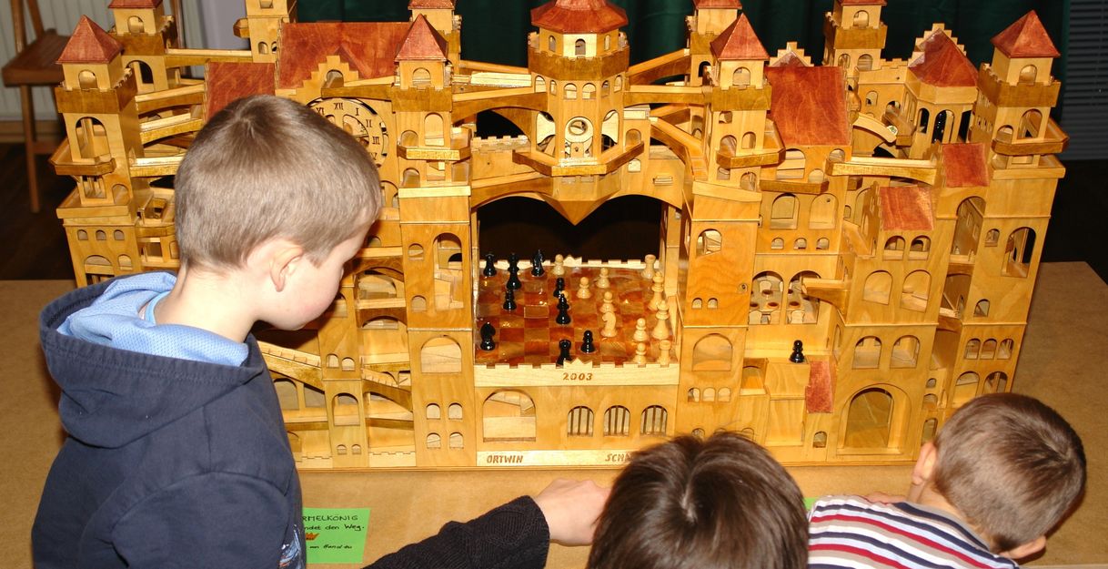 Familie vor einer Murmelbahn in Form einer Fantasie-Burg mit vielen Türmen