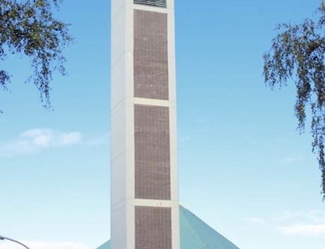Moderne Kirche mit hohem, schlanken Turm und dreieckigem Dach.