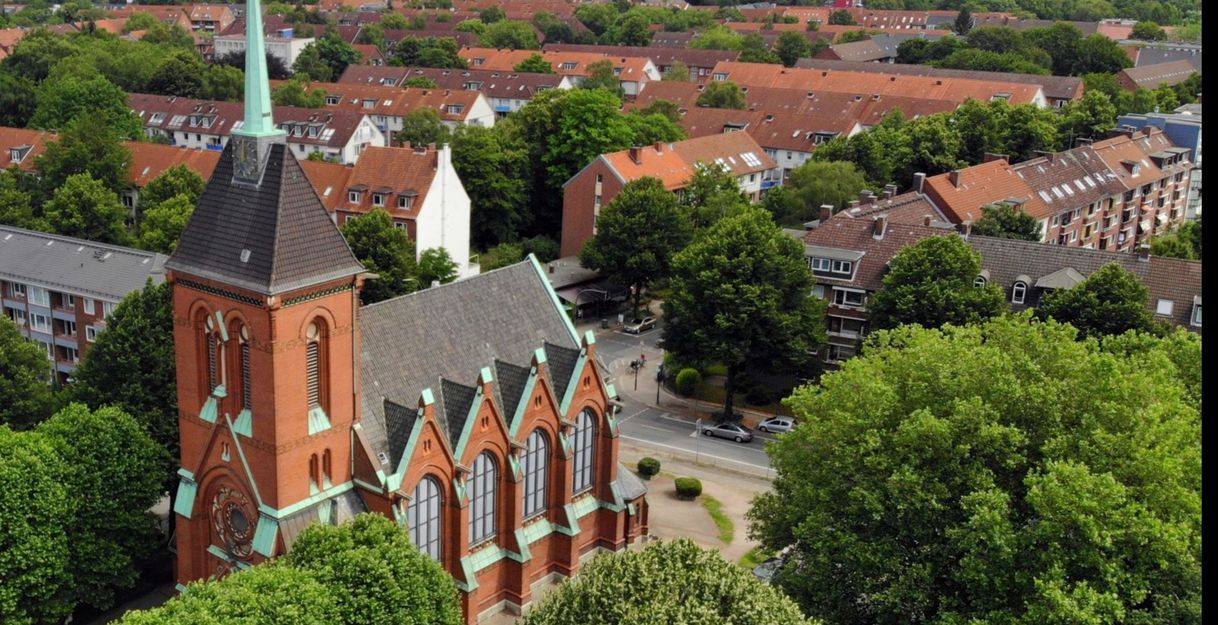 Luftaufnahme einer Kirche inmitten einer Wohngegend mit vielen Bäumen.