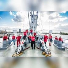 Gruppe von Menschen in roten Outfits auf einem Schiff.