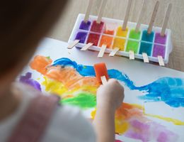 Rückansicht eines mit Aquarellfarben malenden Kindes