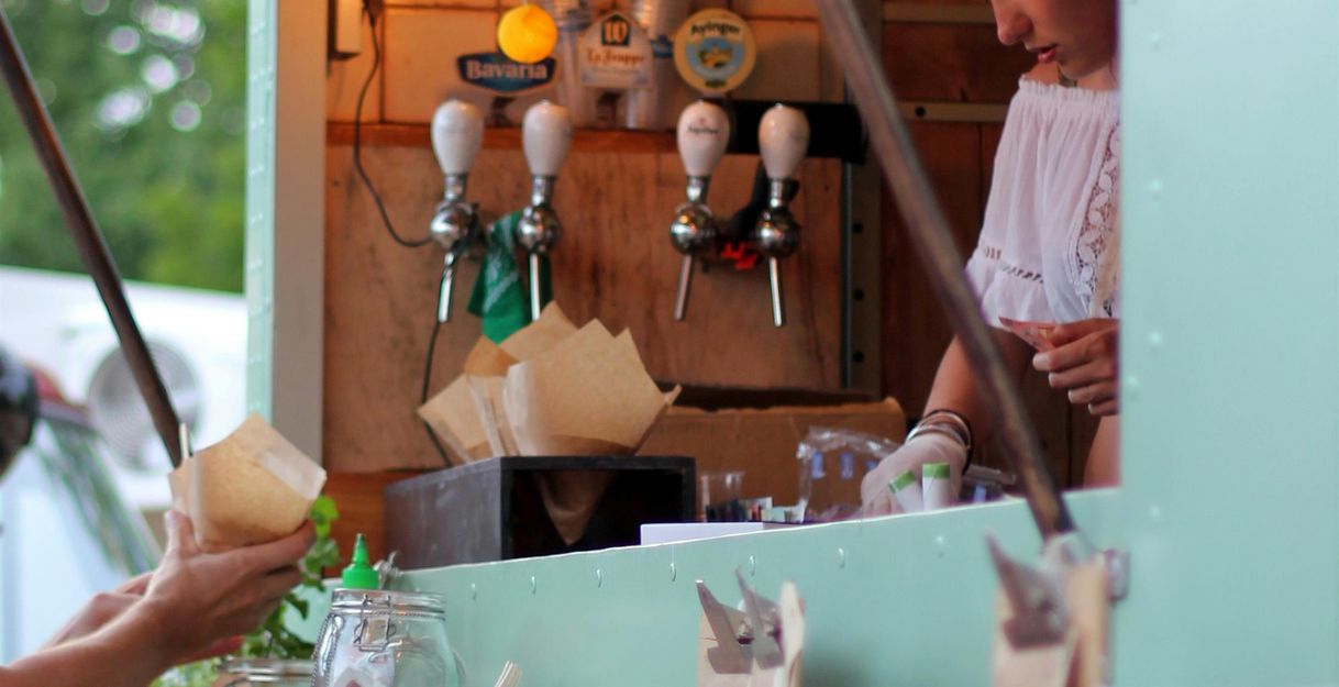 Ein Foodtruck mit bunten Lichtern und Zapfhähnen, in dem eine Frau arbeitet.