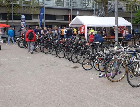 Reihe von Fahrrädern auf einem Flohmarkt mit Menschen im Hintergrund.