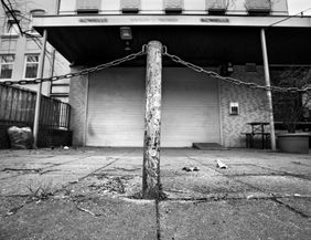 Ein Straßenpoller vor einem geschlossenen Geschäft mit heruntergelassenem Rollladen