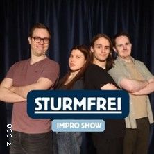 Vier Personen posieren vor einem blauen Vorhang mit dem Logo 'Sturmfrei Impro Show'.