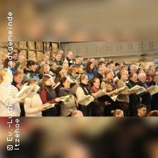 Ein Chor singt in einer Kirche, die Sänger halten Notenblätter in den Händen.