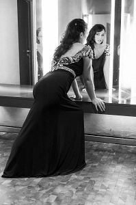 Frau in elegantem Kleid betrachtet sich im Spiegel.