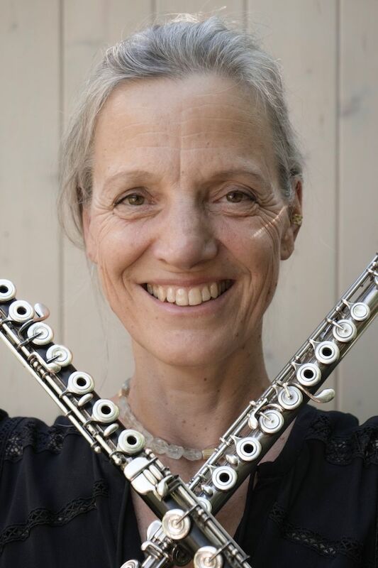 Frau mit zwei Querflöten vor hellem Hintergrund.