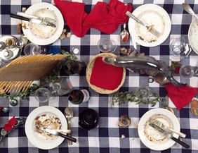 Kunstinstallation von Daniel Spoerri mit benutztem Geschirr auf kariertem Tischtuch.