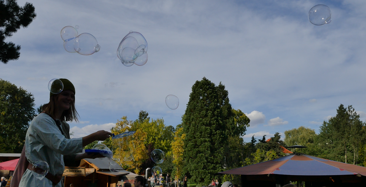 Person erzeugt Seifenblasen auf einem Festival im Freien.