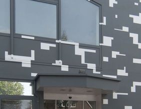 Fassade eines modernen Gebäudes mit grauen und weißen geometrischen Mustern.