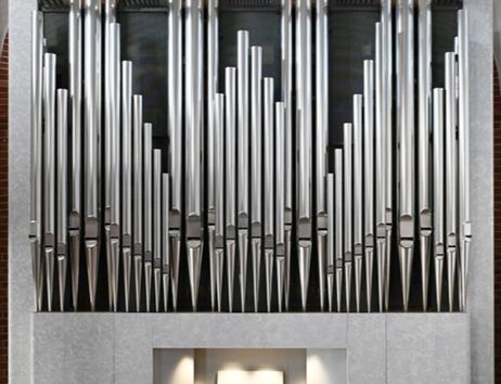 Moderne Orgel mit großen silbernen Pfeifen und einem beleuchteten Spieltisch.