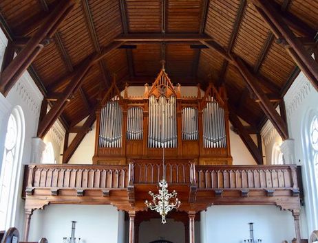 Innenansicht einer Kirche mit hölzerner Orgel und Bänken.