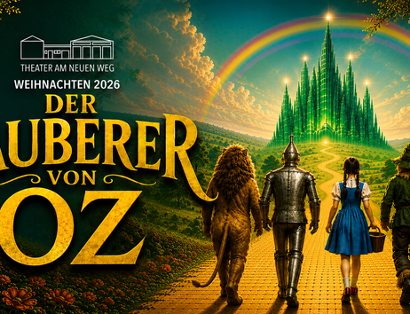 Plakat für das Theaterstück 'Der Zauberer von Oz' mit vier Figuren auf einem gelben Ziegelweg, der zu einer smaragdgrünen Stadt führt, unter einem Regenbogen.