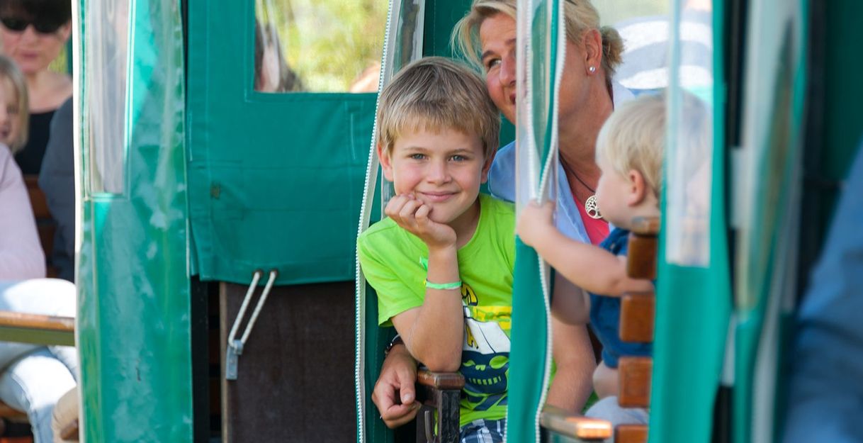 Kinder und Erwachsene in einer grünen Moorbahn während einer Fahrt.