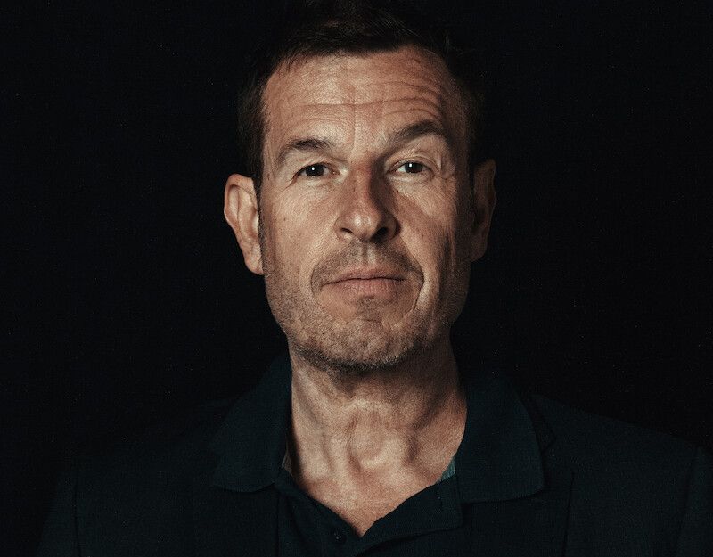 Porträt eines Mannes vor schwarzem Hintergrund.