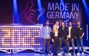 Gruppe von sechs Personen auf einer Bühne mit dem Schriftzug 'Made in Germany live'.