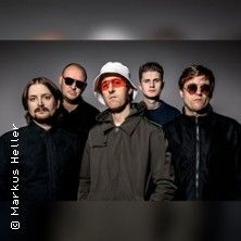 Fünf Männer posieren in dunkler Kleidung vor einem neutralen Hintergrund.