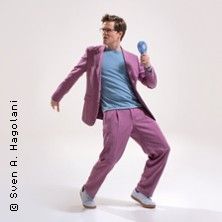 Person in lila Anzug mit Mikrofon in dynamischer Pose.