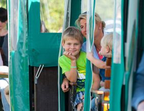 Kinder und Erwachsene in einer grünen Moorbahn während einer Fahrt.