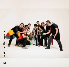 Eine Gruppe von Menschen posiert fröhlich in einem Studio vor einem weißen Hintergrund.