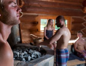 Menschen entspannen in einer Sauna mit Holzwänden.
