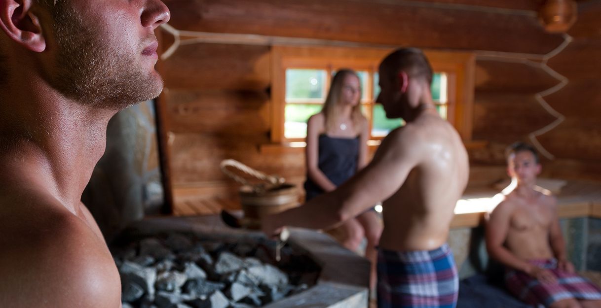 Menschen entspannen in einer Sauna mit Holzwänden.