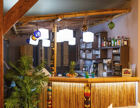 Innenansicht einer Tiki-Bar mit Bambusdekor und tropischen Pflanzen.