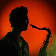 Saxophonspieler im Profil vor rotem Hintergrund