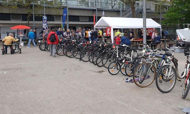 Reihe von Fahrrädern auf einem Flohmarkt mit Menschen im Hintergrund.
