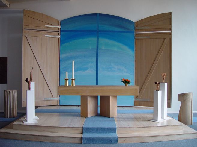 Moderner Kirchenaltar mit blauem Hintergrund und Holzverkleidung.